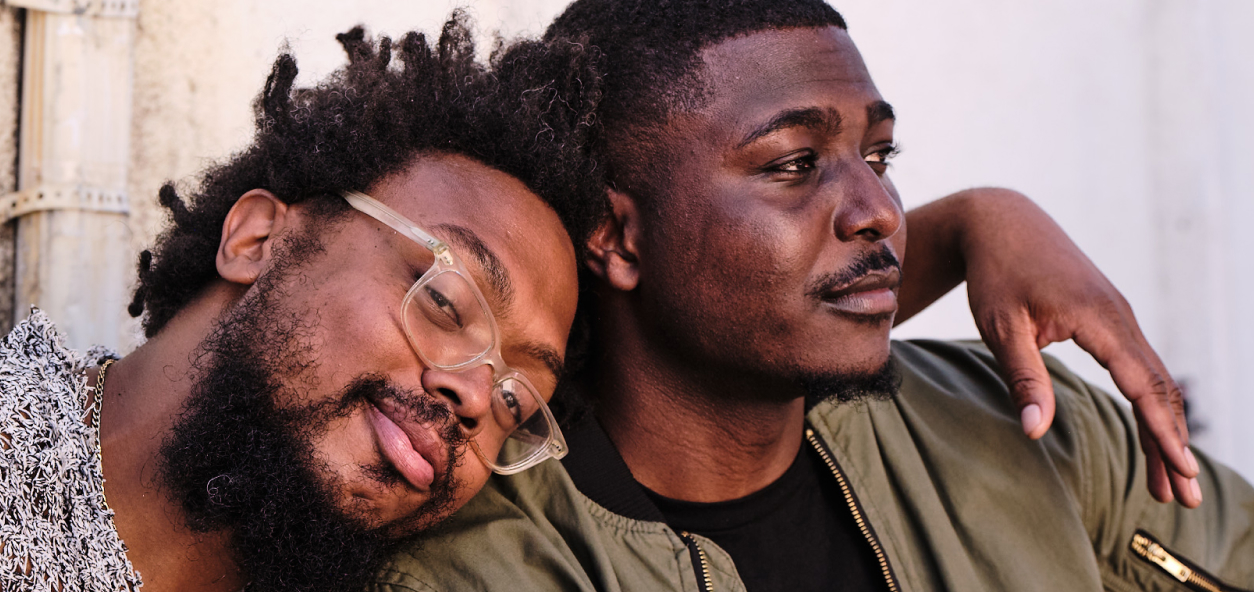 Offering Support and Resources' Together image, two men hugging, looking off into distance, full color